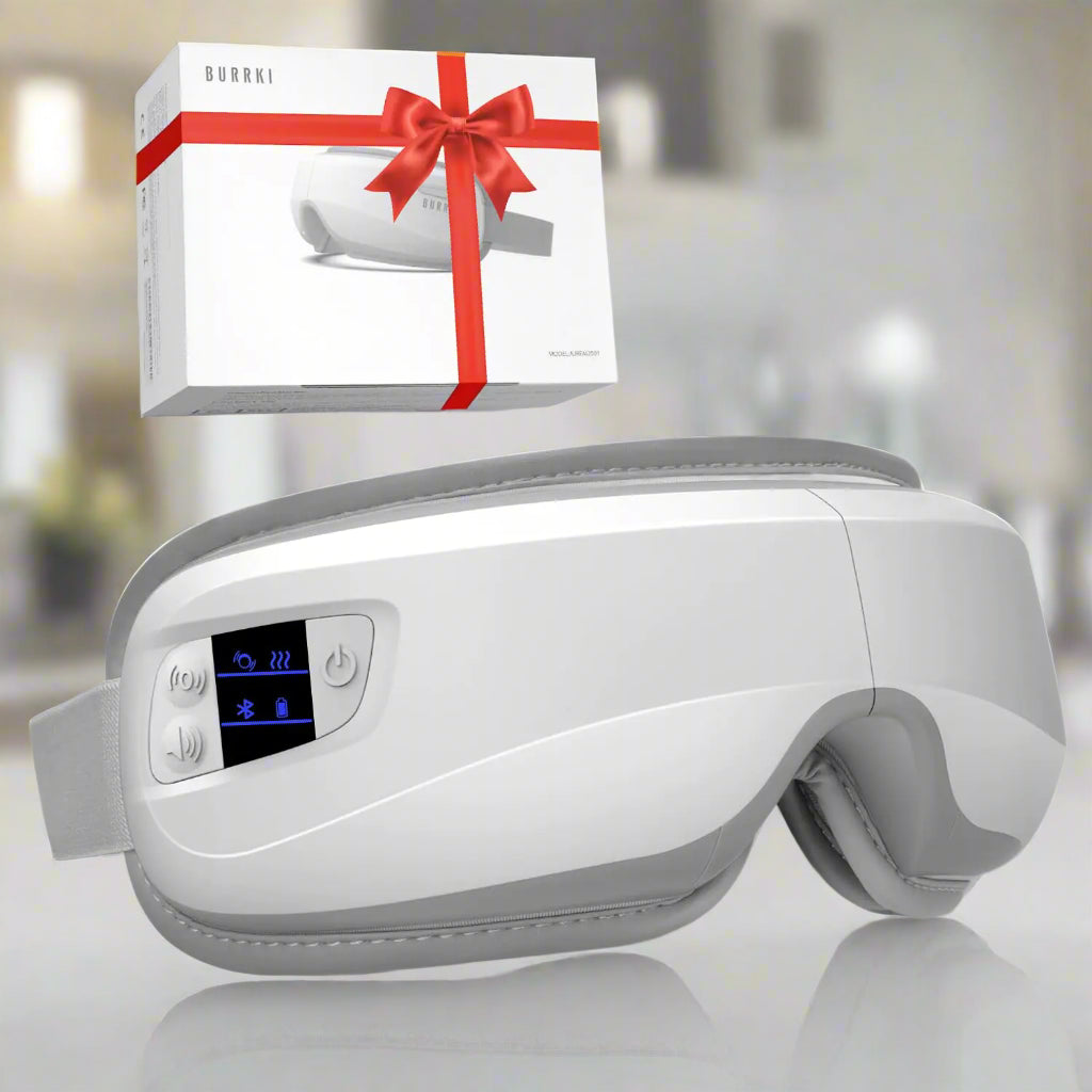 White eye massager with digital display and control buttons, next to a white box with a red bow on a white background.
